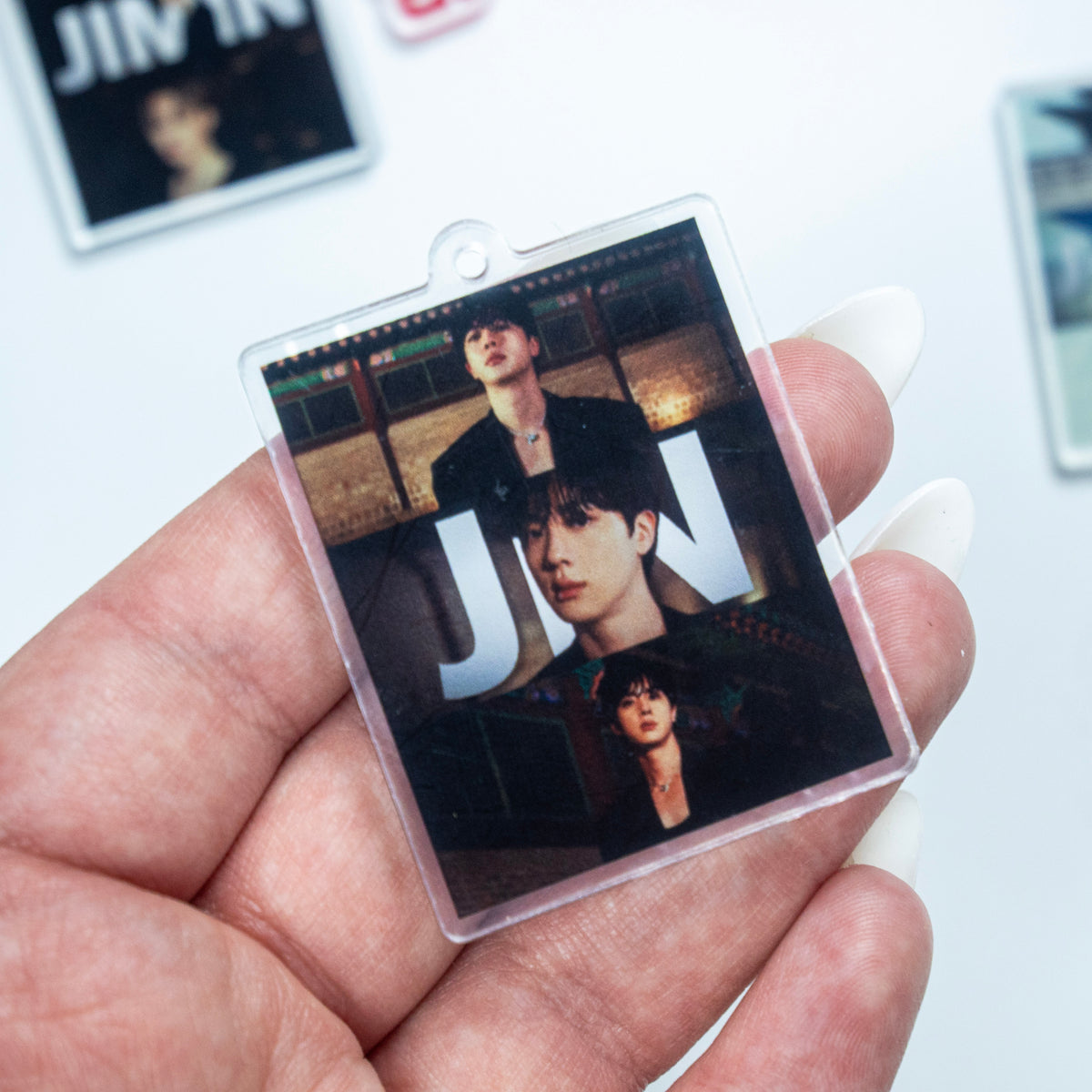 BTS ARIRANG red rope wristlet keychain with red hardware, Jimin acrylic photo charm, and JIN member photo charm options on a white background.