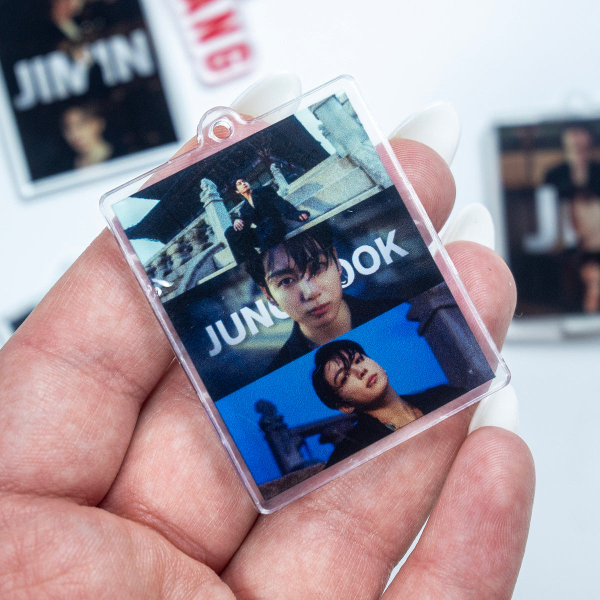 BTS ARIRANG red rope wristlet keychain with red hardware, Jimin acrylic photo charm, and JUNGKOOK member photo charm options on a white background.