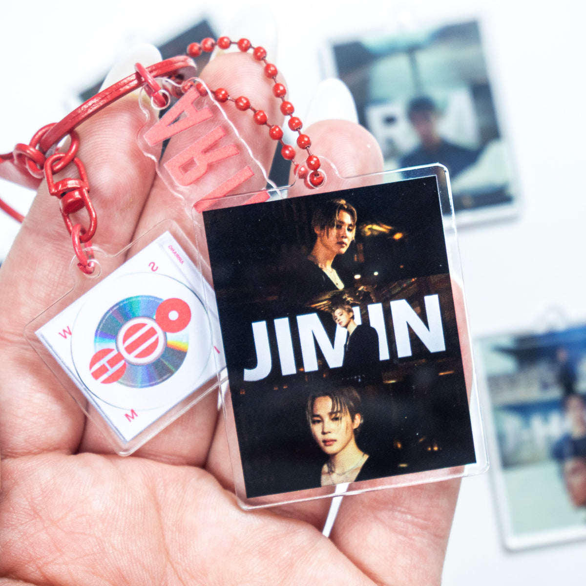 BTS ARIRANG red rope wristlet keychain with red hardware, Jimin acrylic photo charm, and JIMIN member photo charm options on a white background.