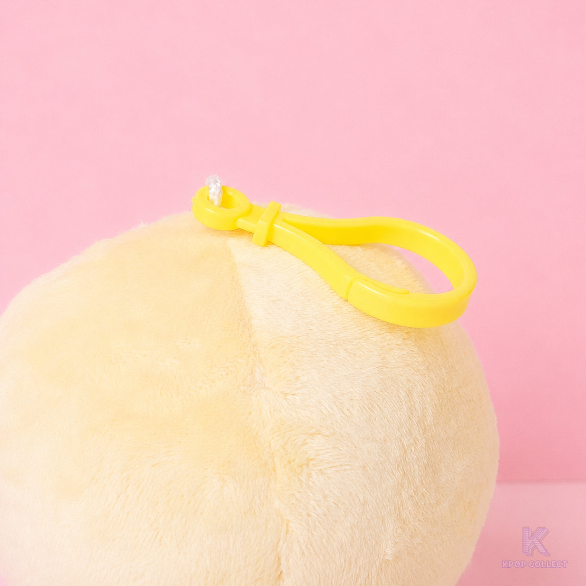 A close-up detail of the yellow attachment clip on the top of the fluffy Stray Kids Felix BbokAri plush keychain