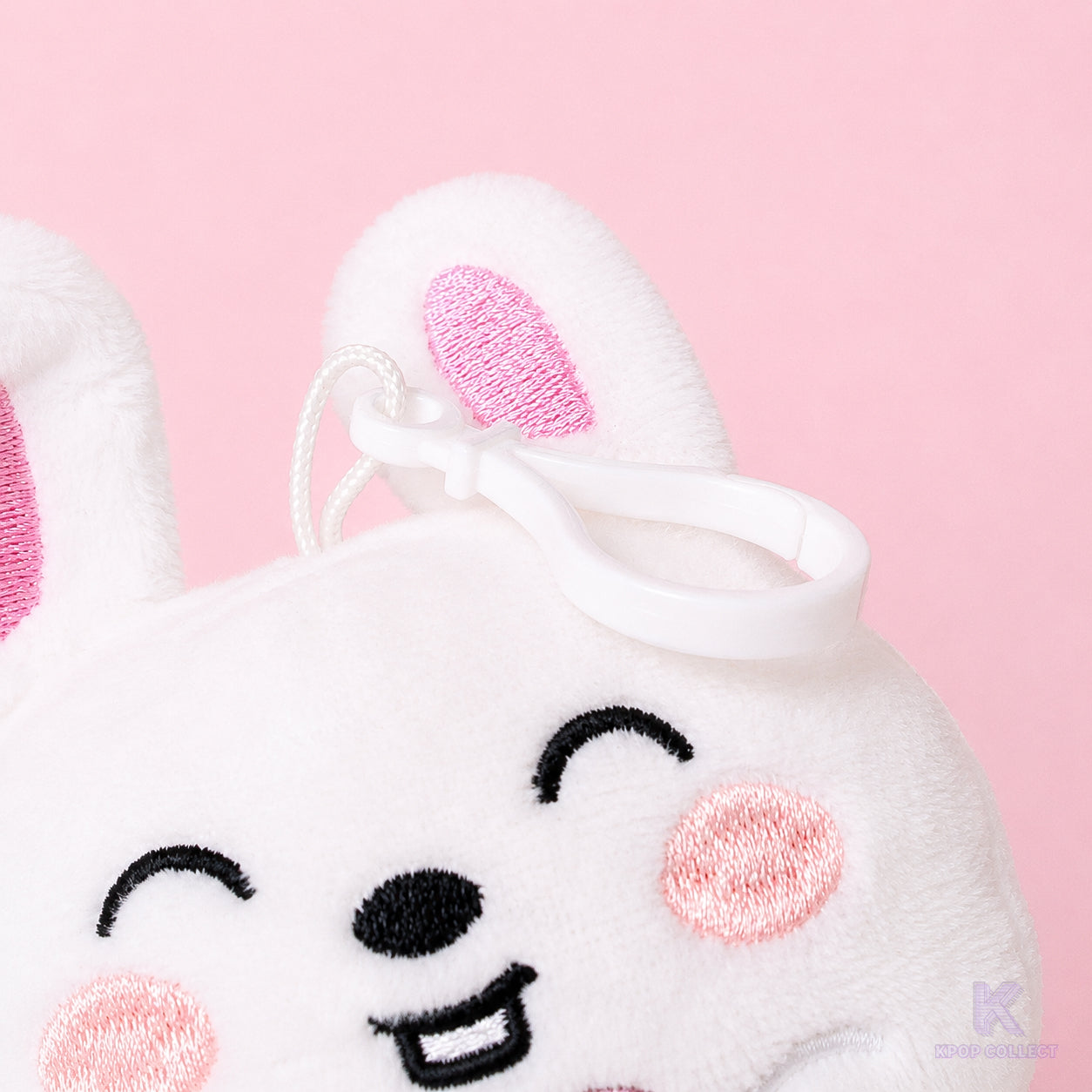 A close-up detail of the attachment clip on the top of the fluffy Stray Kids Lee Know Leebit plush keychain, showing the hardware and the bunny's face.